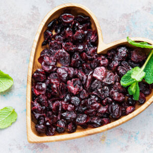 Wooden bowl full of sweet dried cherries on grey concrete background