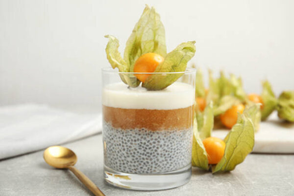 Delicious chia pudding decorated with physalis on light grey table