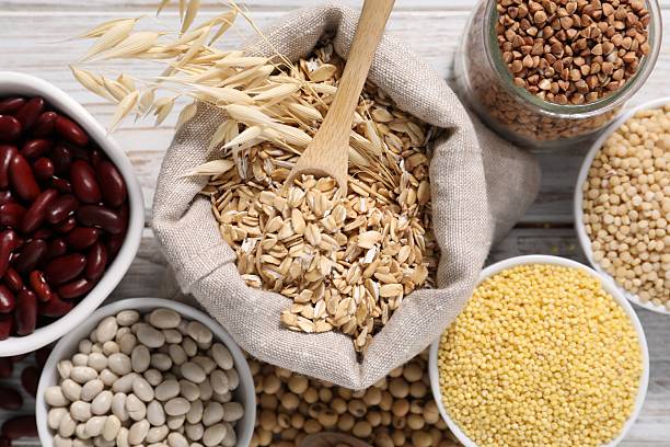 Different types of legumes and cereals on white wooden table, flat lay
