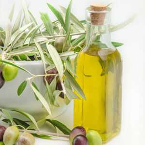 Extra virgin olive oil surrounded by freshly harvested olives